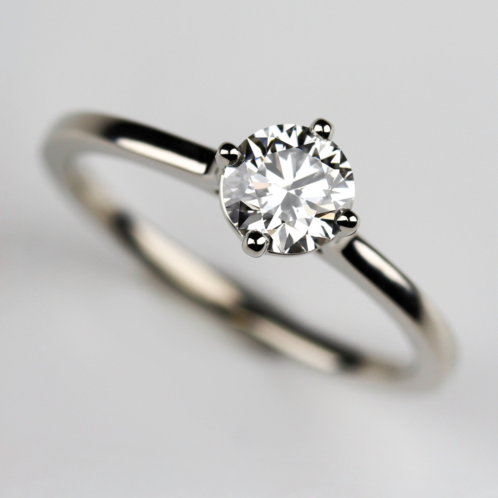 Cathedral solitaire in shiny white gold with a diamond center stone. The prongs have a compass orientation.