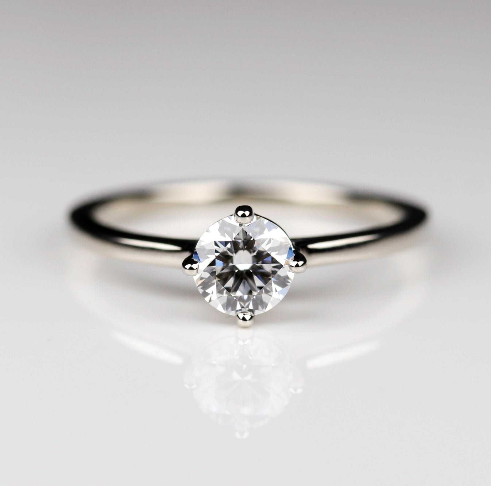 Cathedral solitaire in shiny white gold with a diamond center stone. The prongs have a compass orientation.