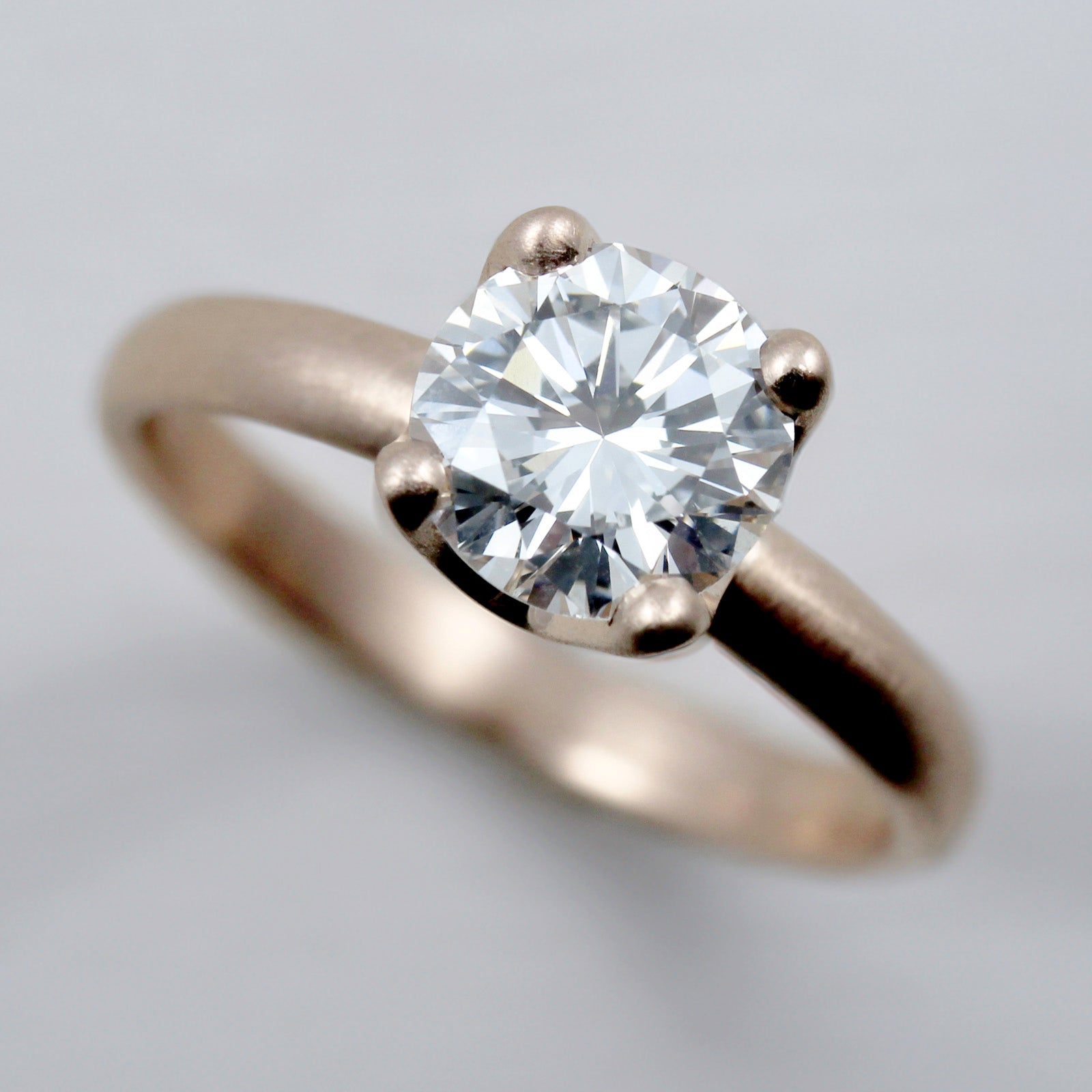 Rose gold solitaire engagement ring with a prong-set white diamond. The center stone is around 7mm in diameter.