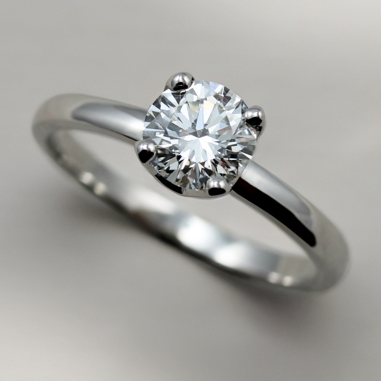 Shiny white gold solitaire engagement ring with a prong-set white diamond. The center stone is around 5mm in diameter.