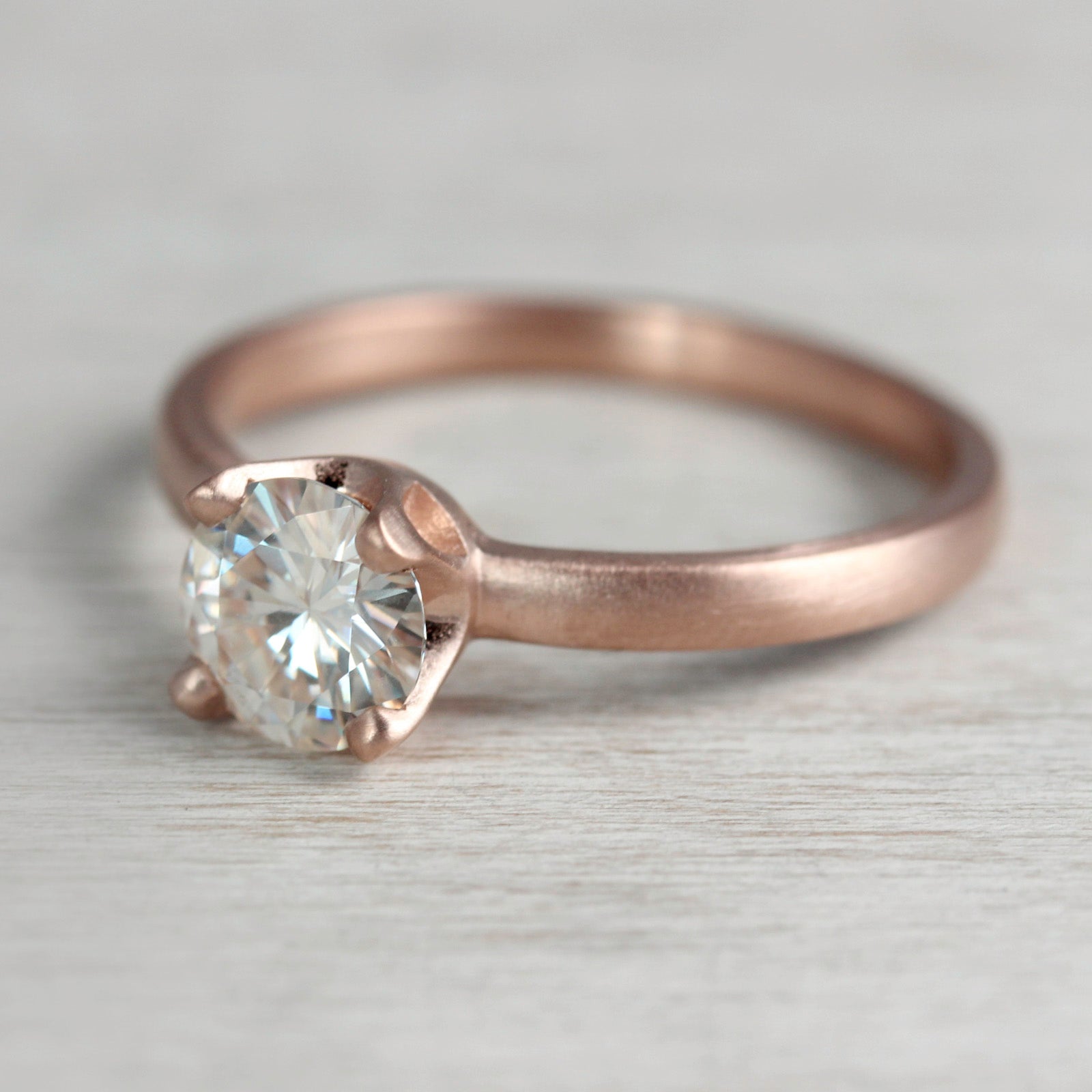 Rose gold solitaire engagement ring with a prong-set white diamond. The center stone is about 5mm in diameter.