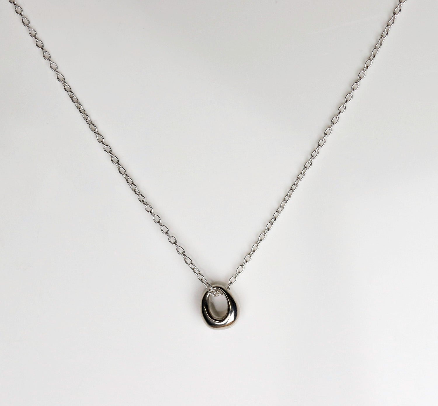 A sterling silver necklace with a circular pendant.