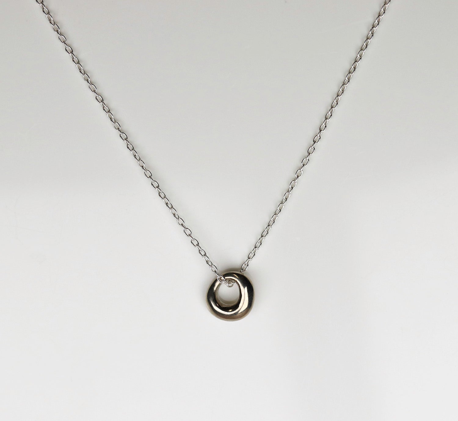 A sterling silver necklace with a circular pendant.
