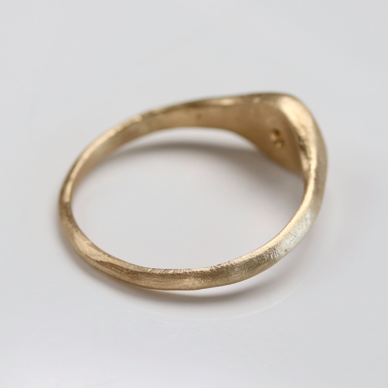 Back angle of a textured signet ring style in matte yellow gold.