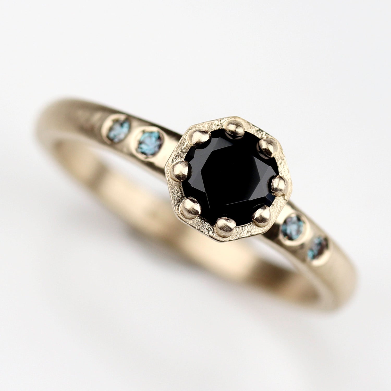 Custom yellow gold engagement ring with a black spinel center and alexandrite accent stones.