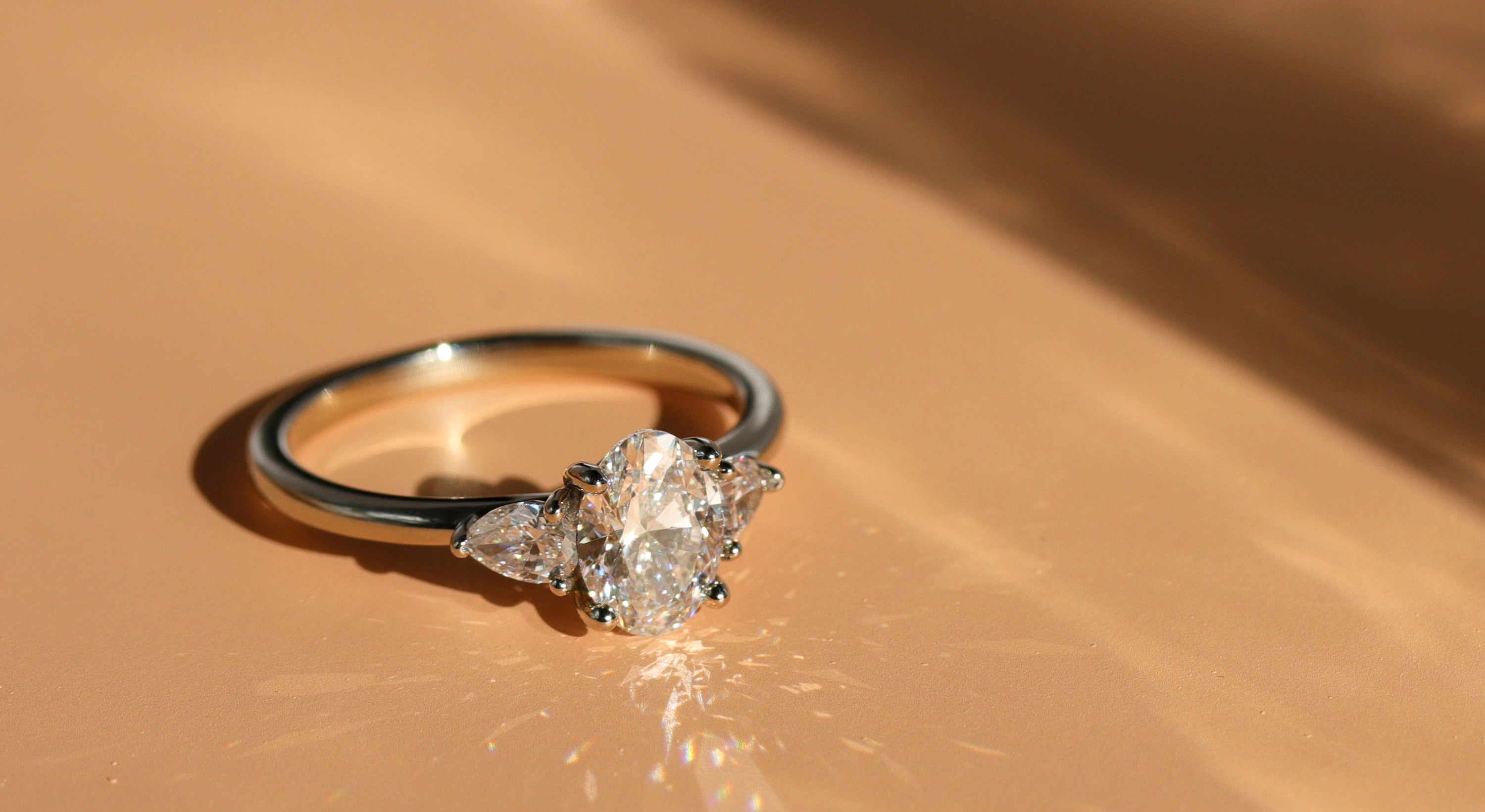 A three stone engagement ring with an oval diamond center stone and pear shaped diamond accent stones.