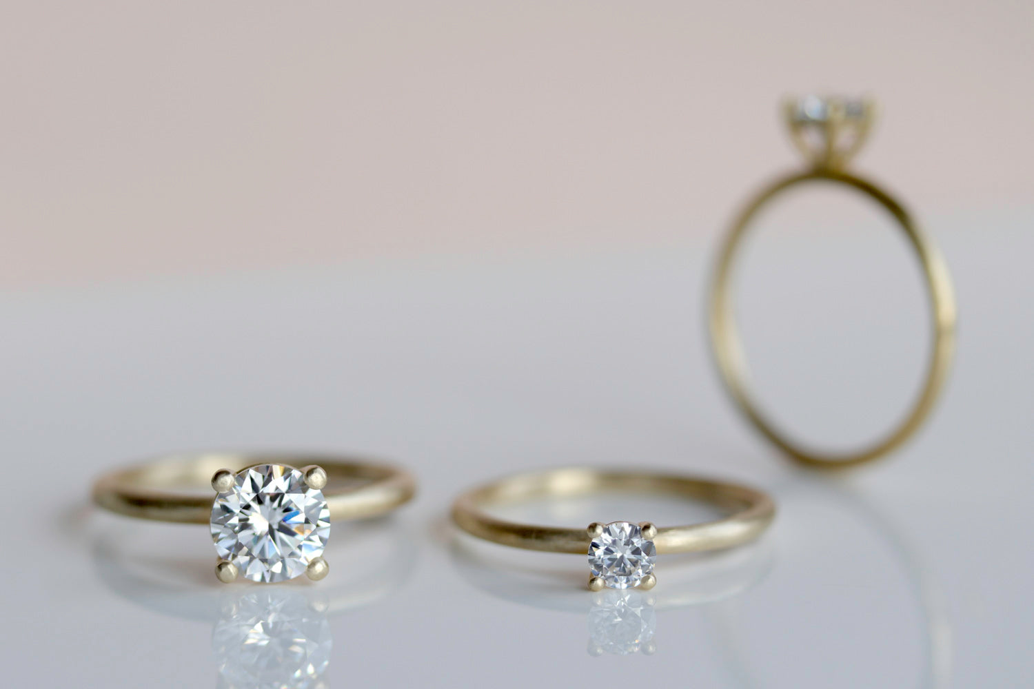 Image shows three solitaire engagement rings to depict the difference between different millimeter-sized center stones.