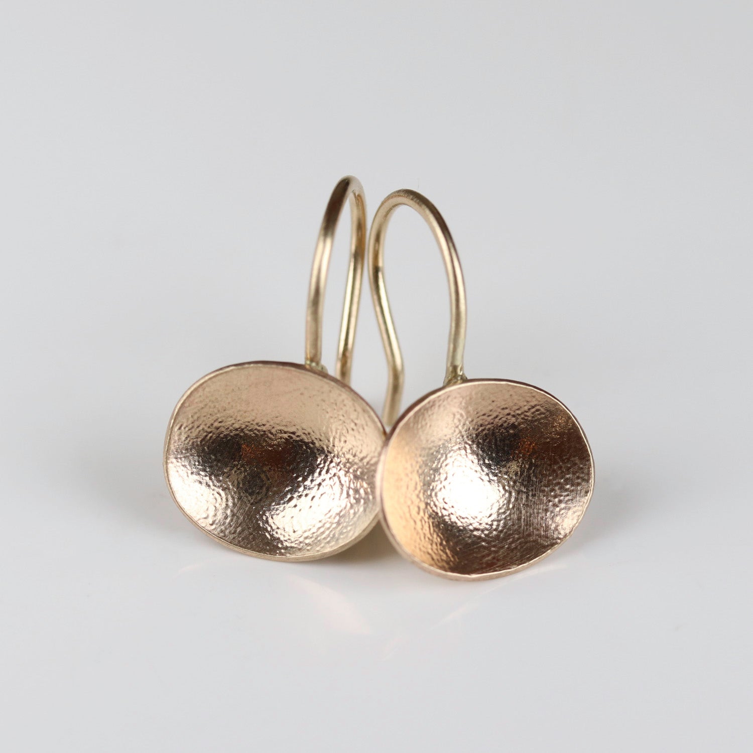 Gold hammer texture disc dangle earrings on a light gray background