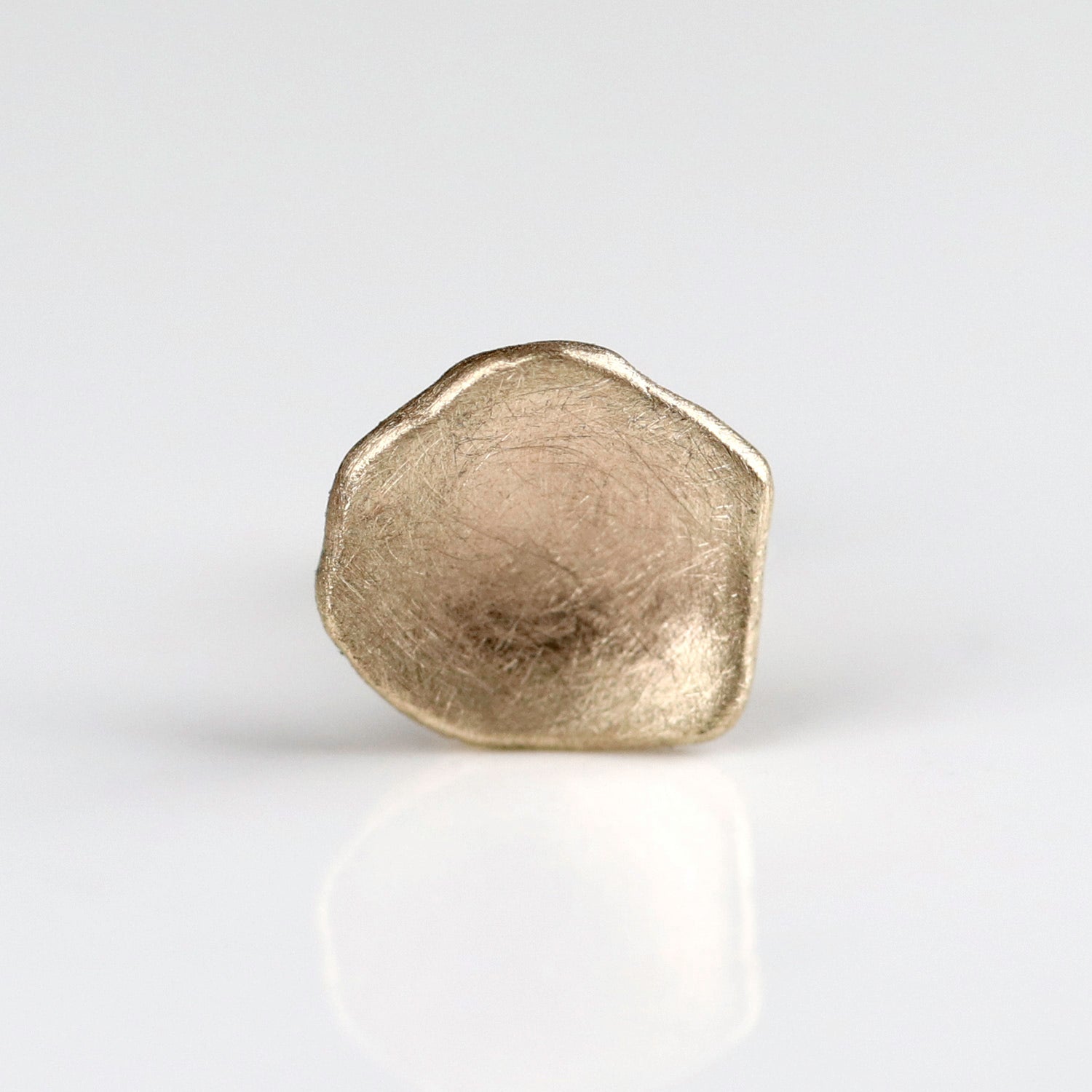 A single gold stud with a domed eggshell shape and a gently textured interior surface.