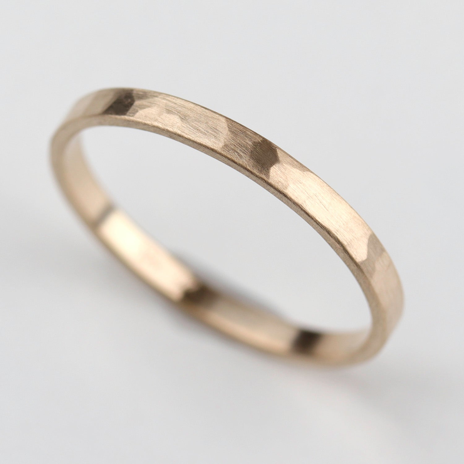 Top view of a narrow hammer texture wedding band in matte yellow gold.