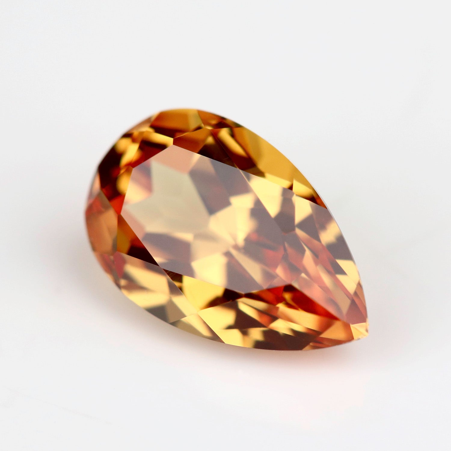 Lab-grown orange sapphire in a pear cut. The stone is a vibrant flame orange tone.