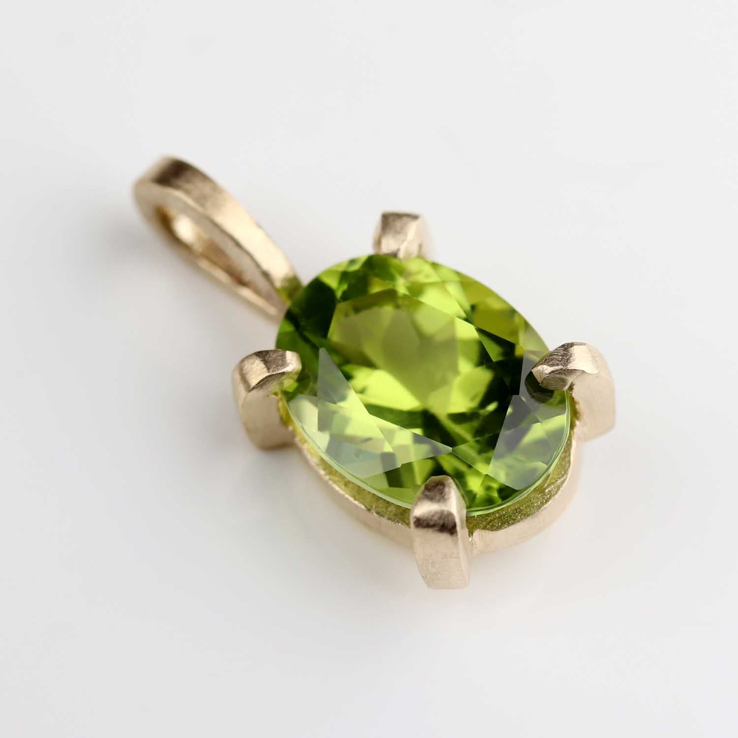 A charm in matte yellow gold with a prong-set oval Arizona peridot.