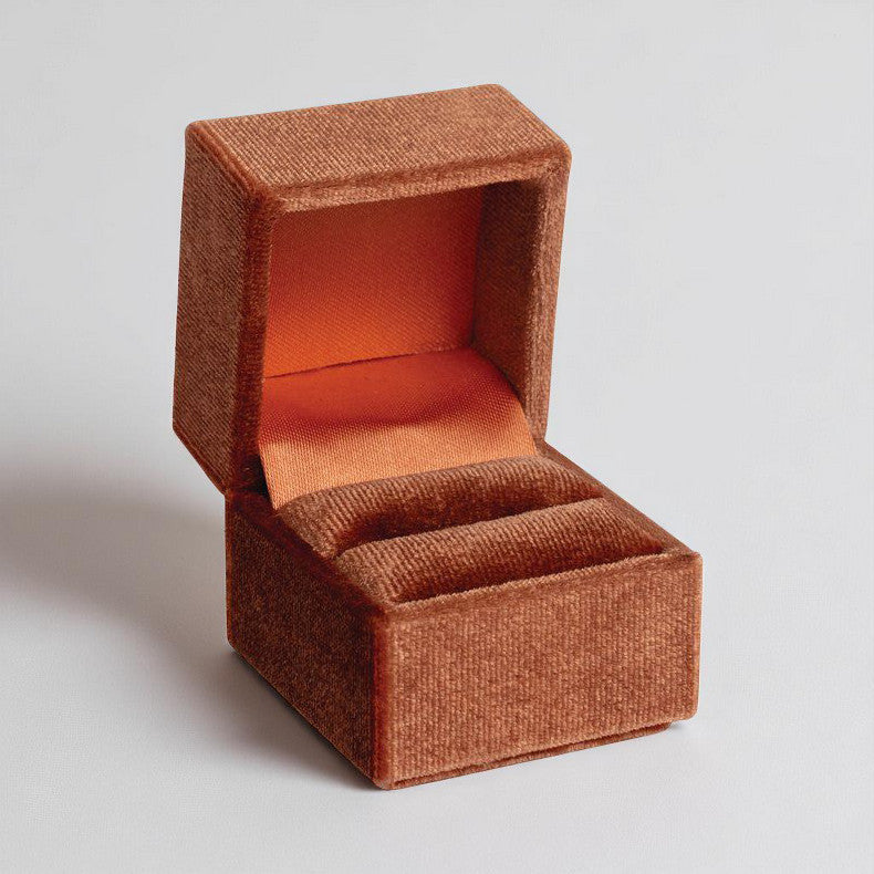 A rust orange velvet clamshell ring box.