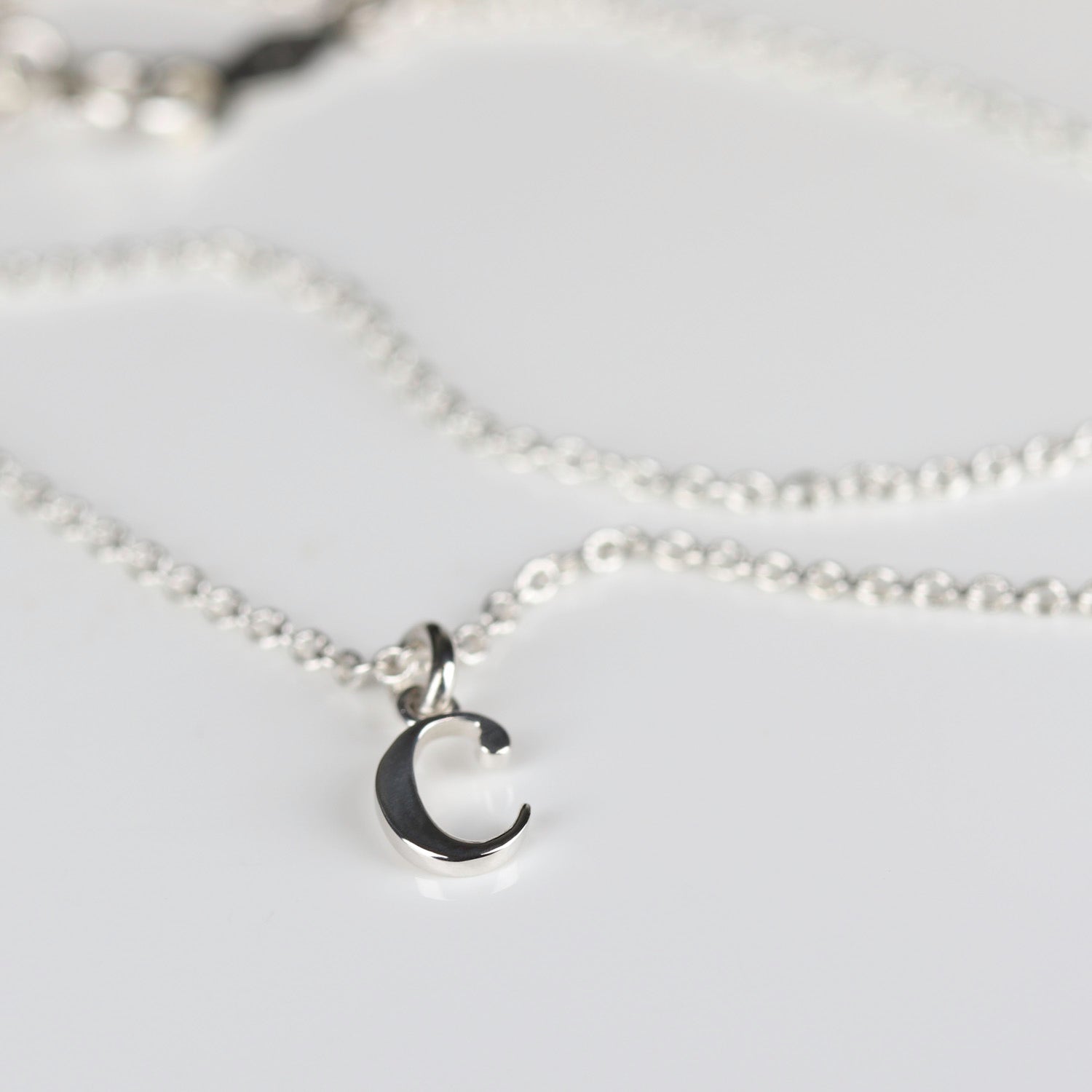 A small lowercase letter C charm on a narrow chain.
