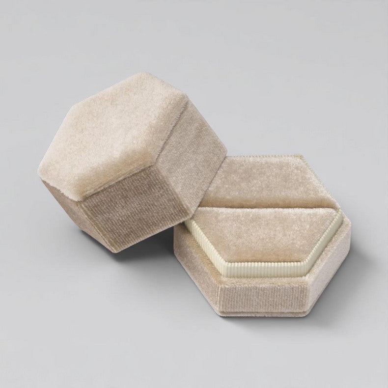 A champagne velvet hexagon shaped ring box.