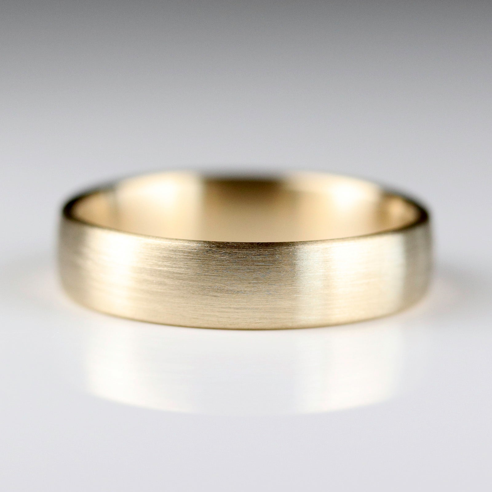 Side angle of a smooth masculine or transmasculine yellow gold band.