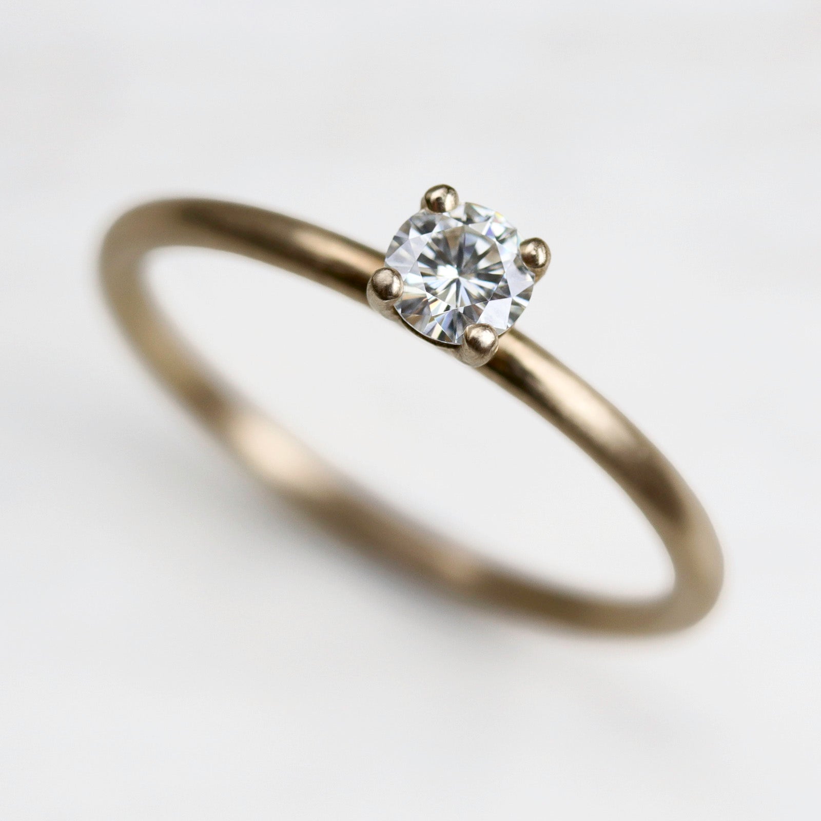 Yellow gold solitaire engagement ring with a prong-set white diamond. The center stone is around 4mm in diameter, and is set in a basket setting.