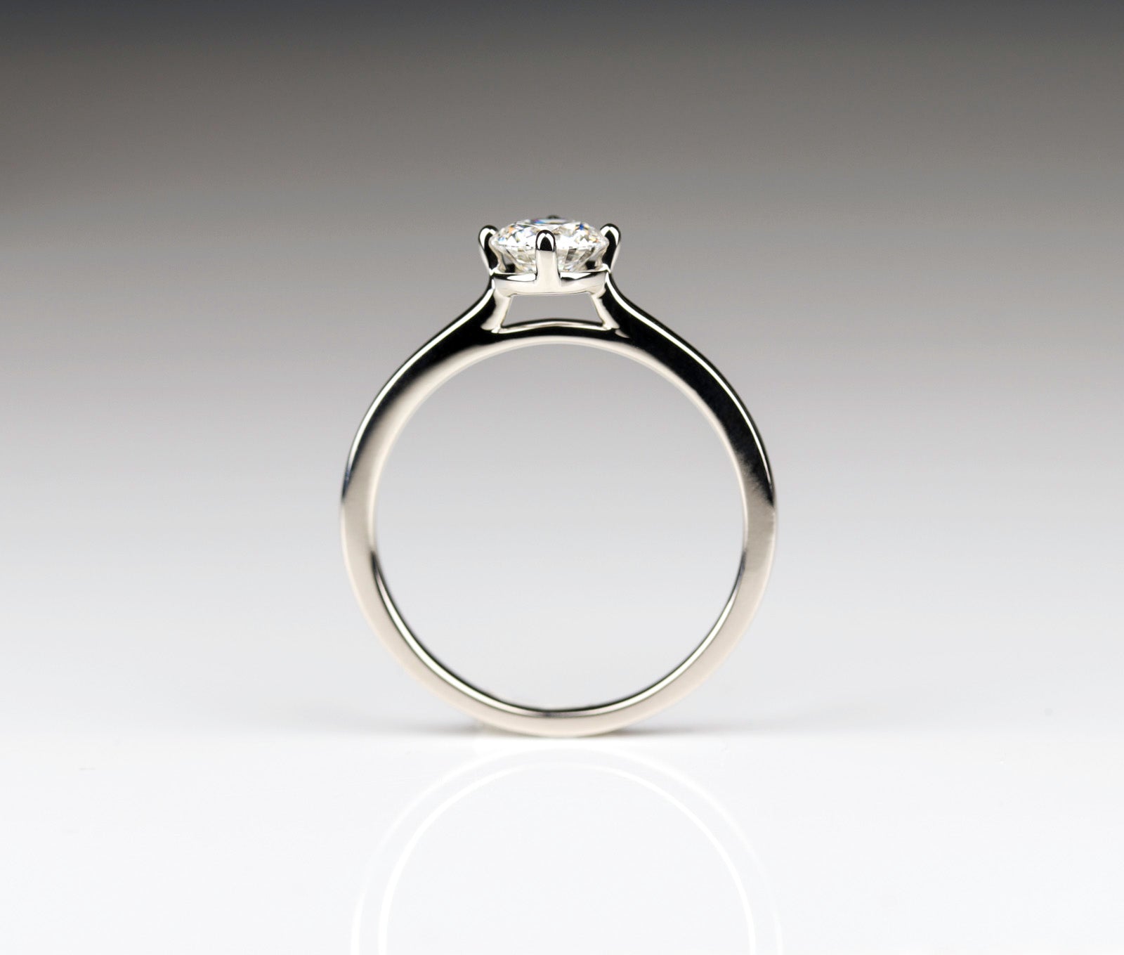Cathedral solitaire in shiny white gold with a diamond center stone. The prongs have a compass orientation.