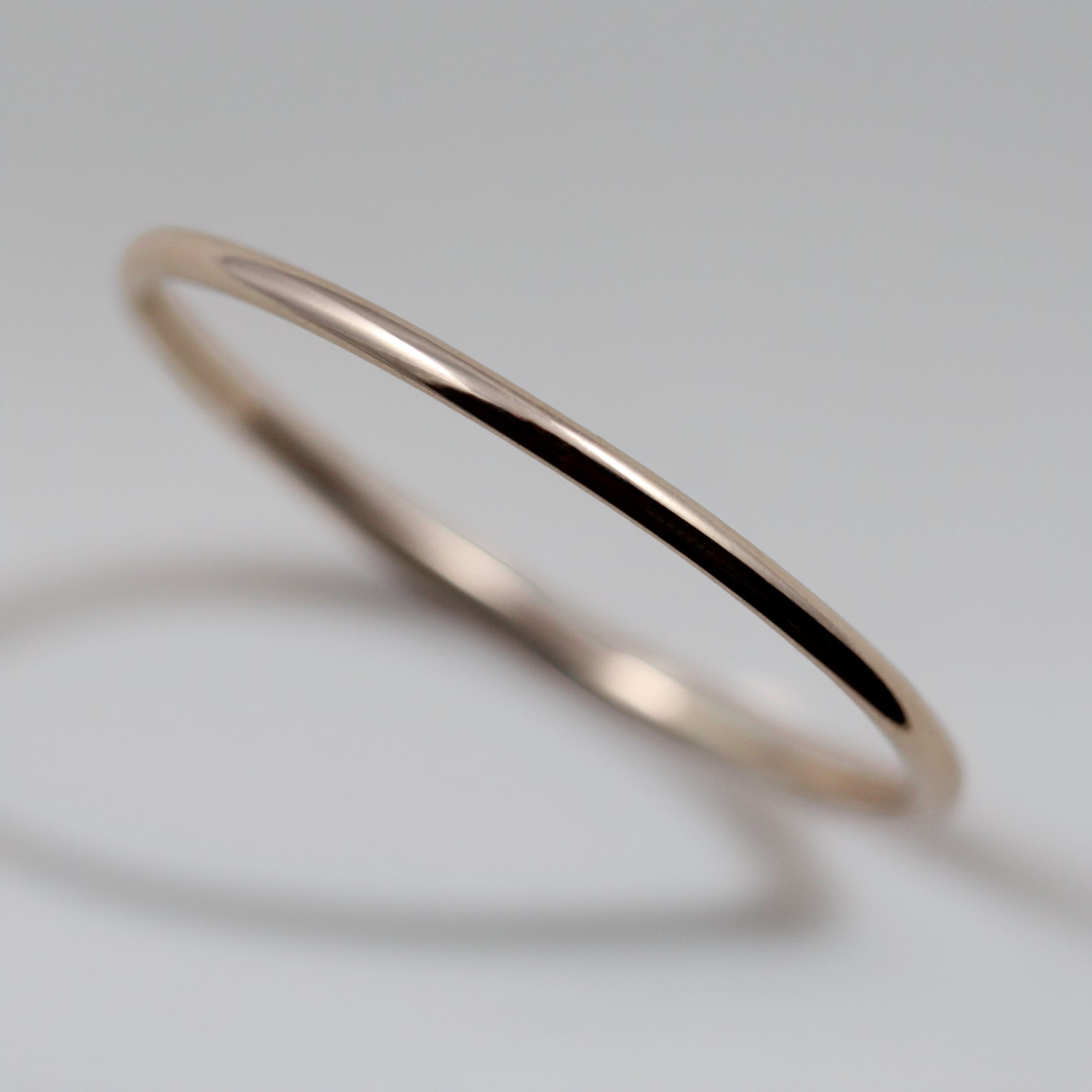 A shiny rose gold stacking ring. This ring has a round profile and measures 1mm in diameter.