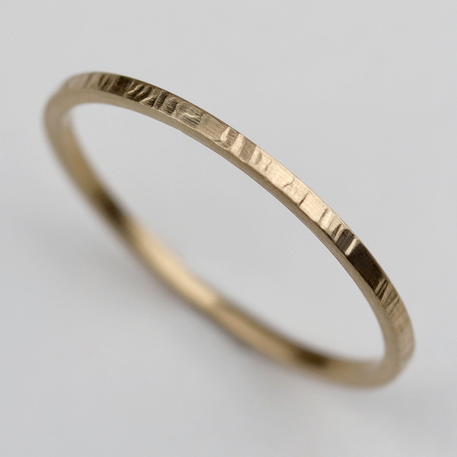 A wood textured stacking ring in yellow gold. 