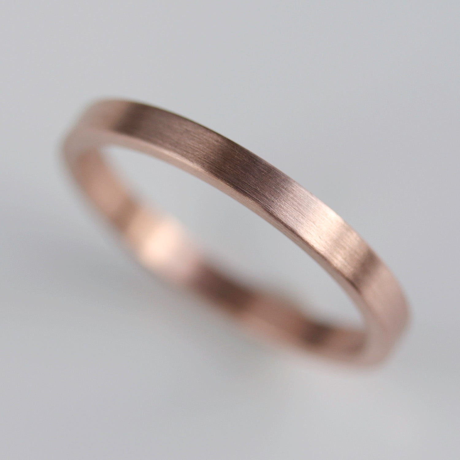 A plain smooth women's wedding band style in matte rose gold.