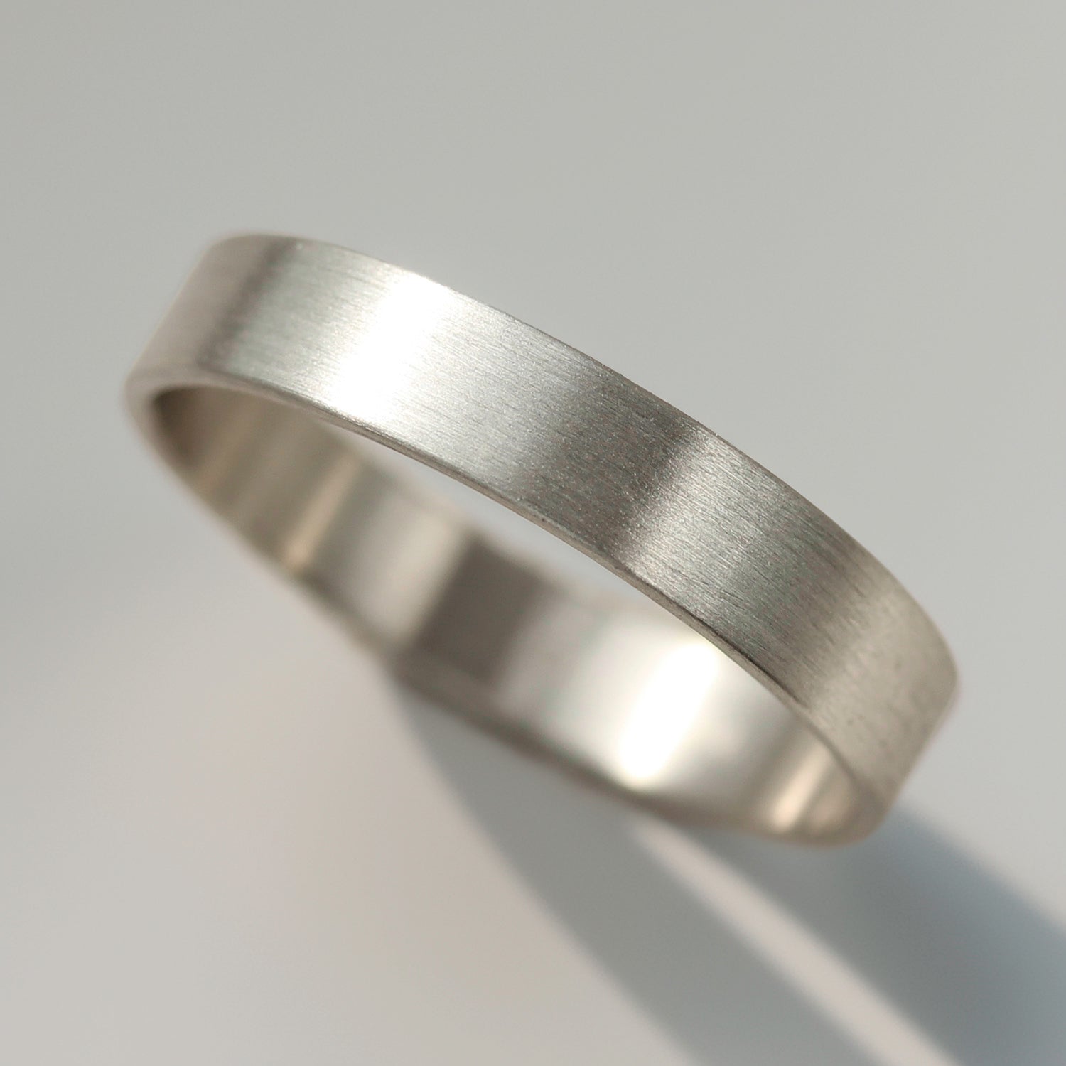 A plain masculine or transmasculine wedding band in 14k white gold.