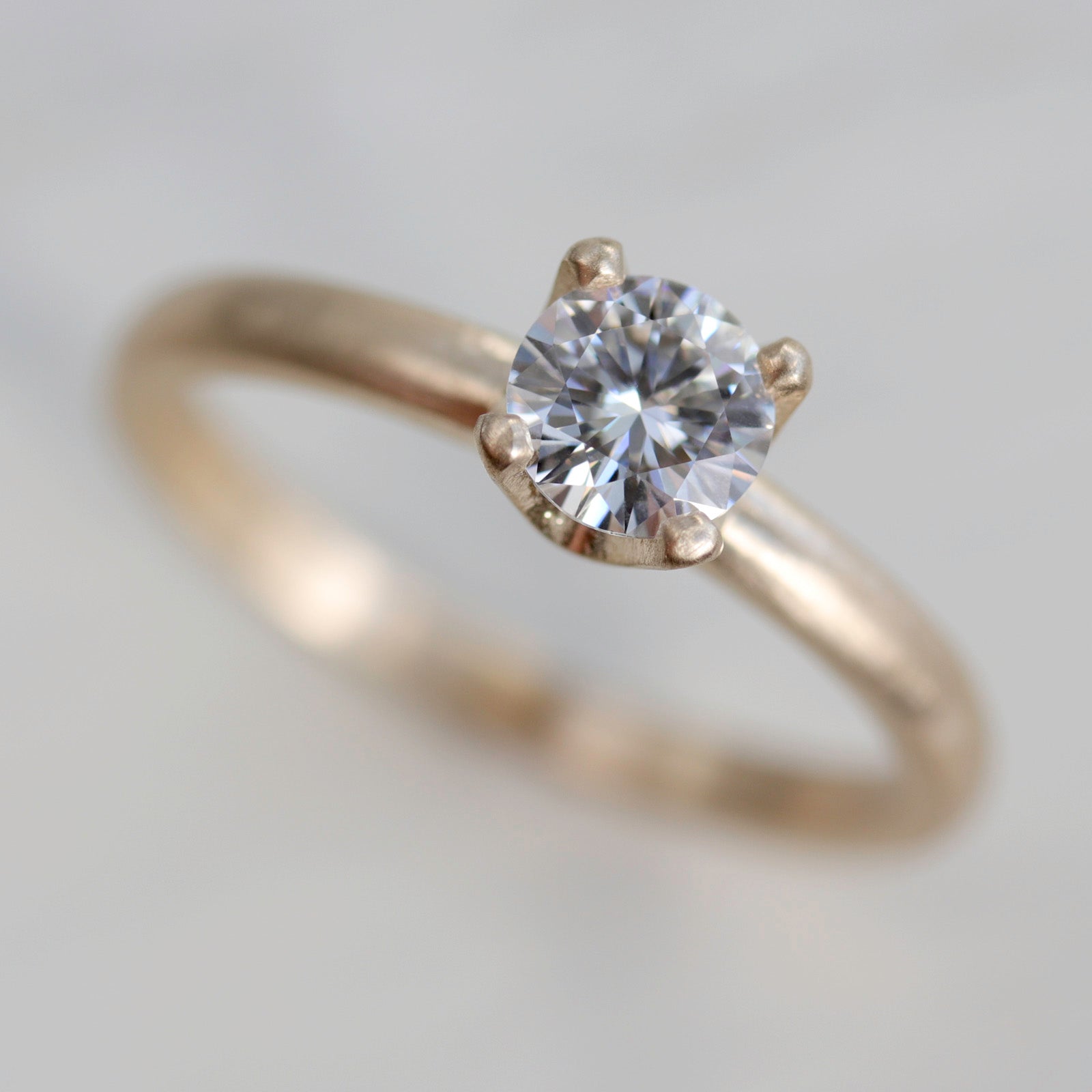 Yellow gold solitaire engagement ring with a prong-set white diamond. The center stone is around 5mm in diameter. 