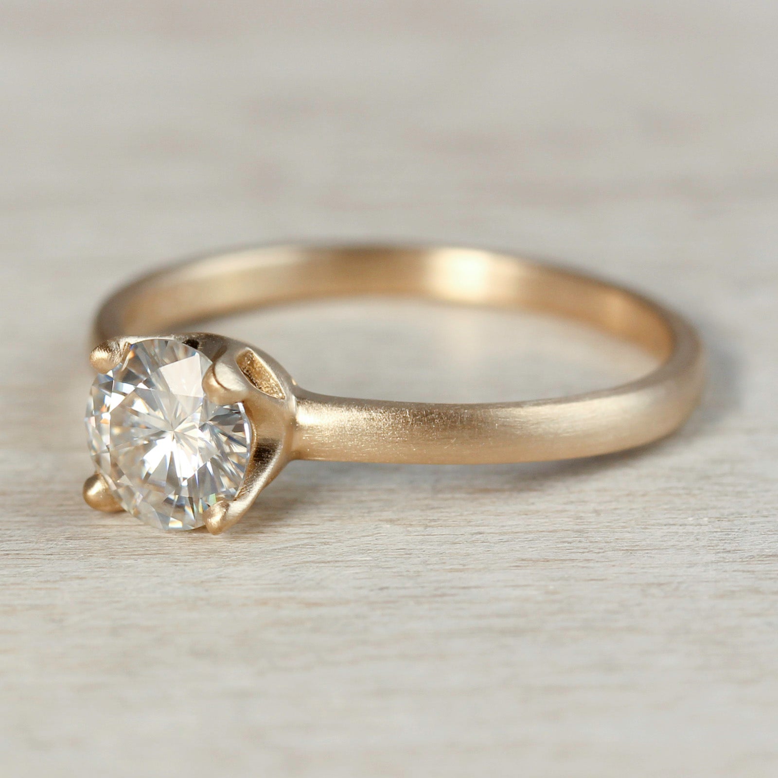 Yellow gold solitaire engagement ring with a prong-set white diamond. The center stone is around 5mm in diameter. 