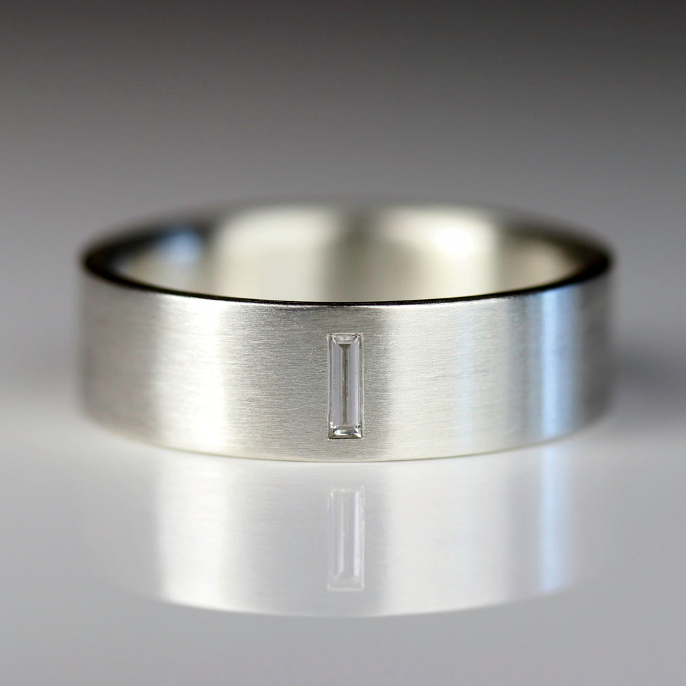 Side angle of a smooth flat men's engagement ring style in sterling silver. The band has a flush set baguette diamond set horizontally.