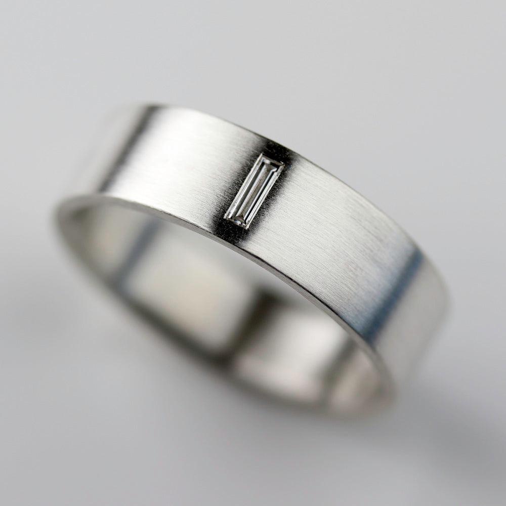 A smooth flat men's engagement ring style in sterling silver. The band has a flush set baguette diamond set horizontally.
