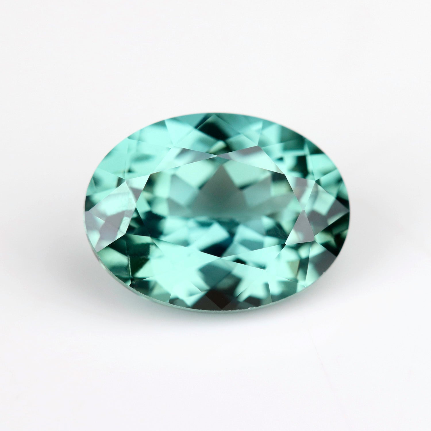 A lab-grown green oval sapphire in a 8x6mm size. The stone is saturated mint green color.