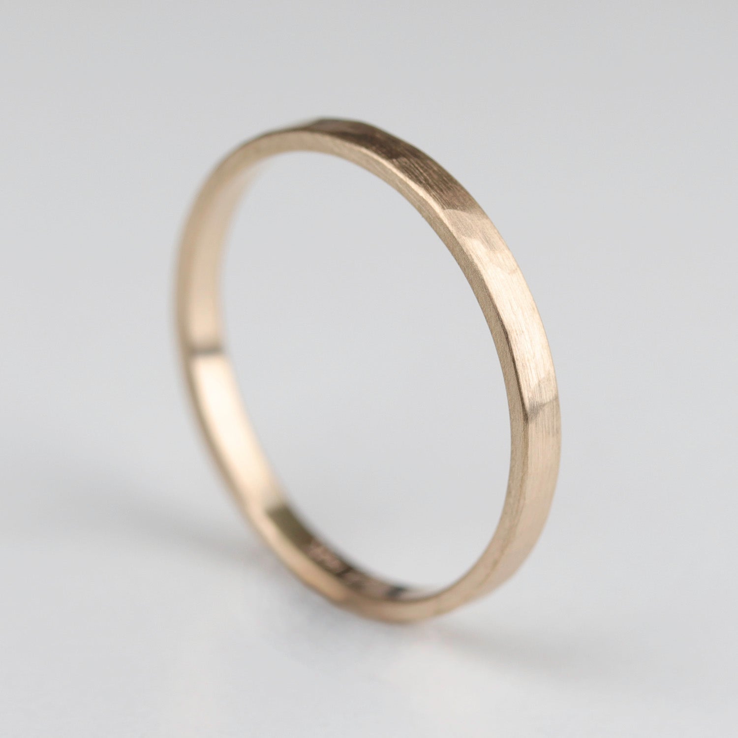 Side angle of a narrow hammer texture wedding band in matte yellow gold.