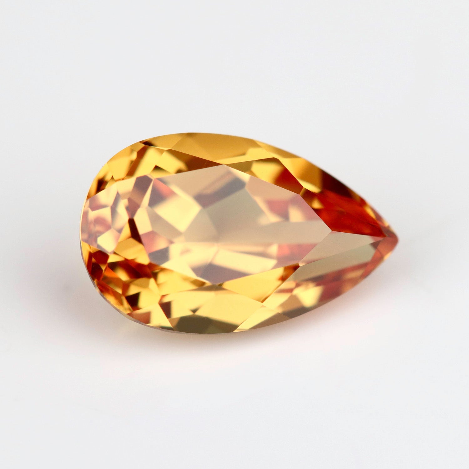 Lab-grown orange sapphire in a pear cut. The stone is a vibrant flame orange tone.