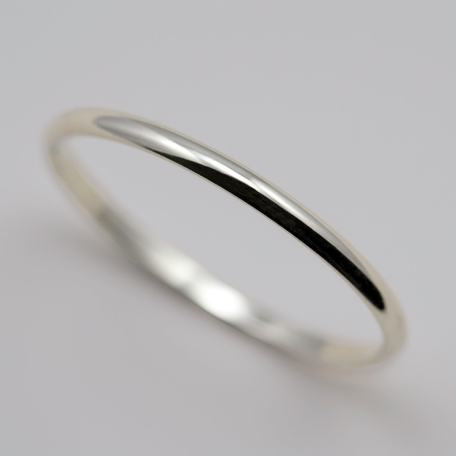 A narrow wedding band in shiny white gold. The ring has a half-round profile.