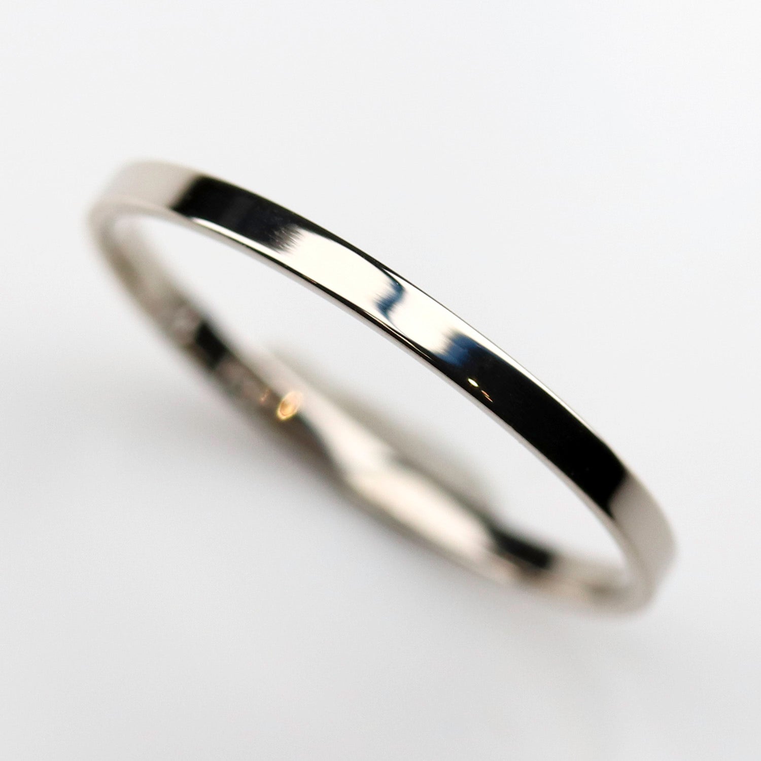 A shiny white gold wedding band. The ring is very narrow and has a slim-fitting profile.